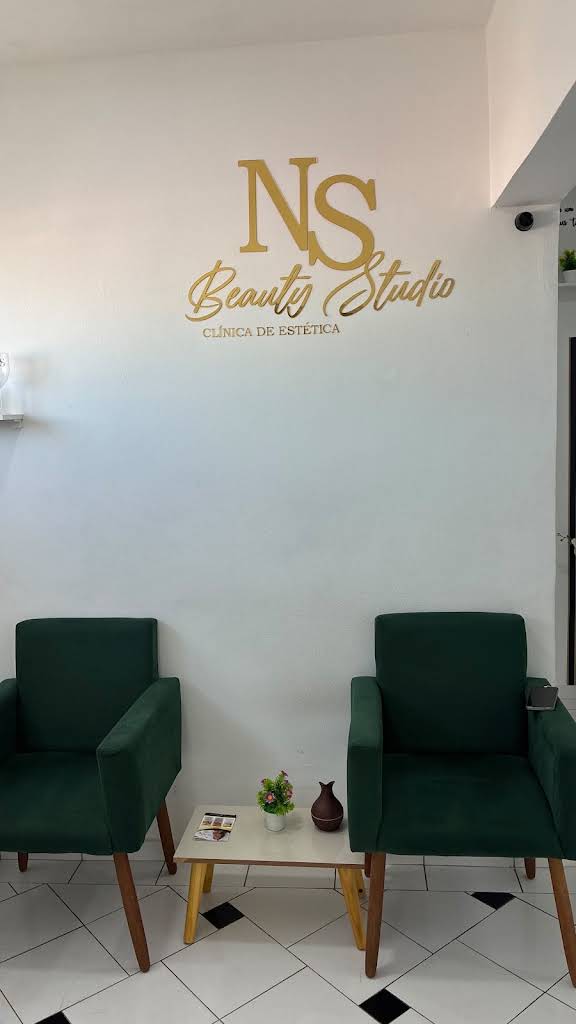 Recepção da NS Beauty Studio com o logotipo da clínica e poltronas verdes